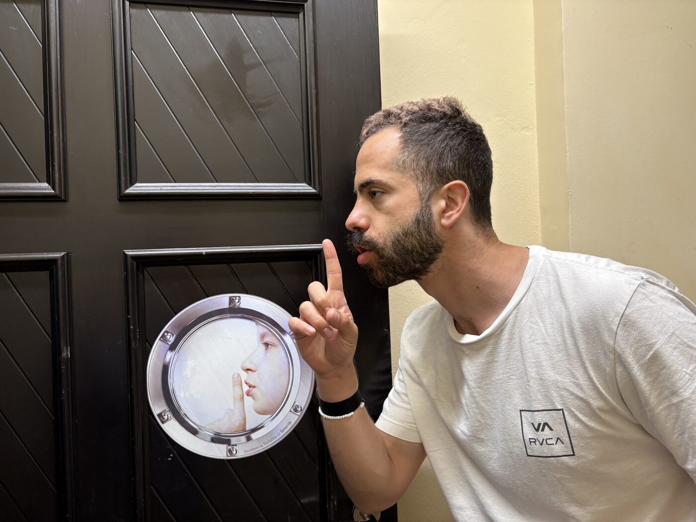 Orfeas making a shushing gesture beside a matching sign