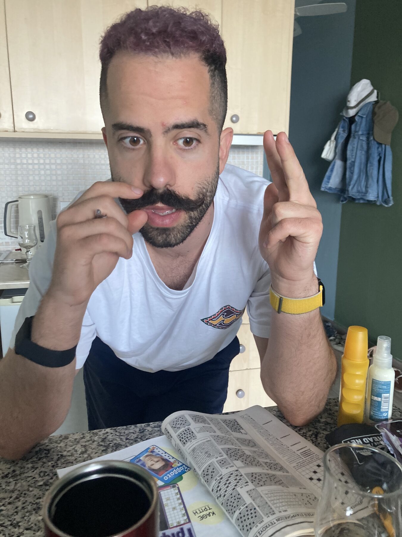 Orfeas styling his moustache over an open newspaper puzzle